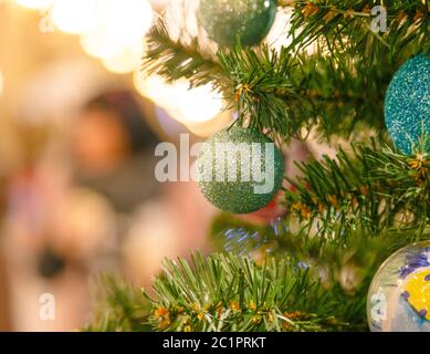 Decorated Christmas tree on blurred background. Close up of baubles and branch at New Year fir tree Stock Photo