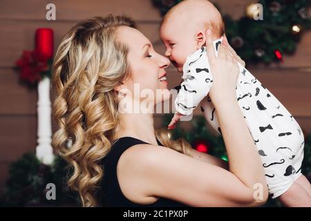 Boy with beautiful blonde mom embracing in decorated studio for Christmas. Stock Photo