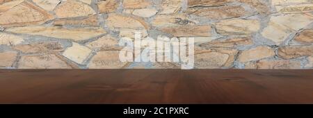 Old brown wood table with blurred stone block wall in light room background. Stock Photo