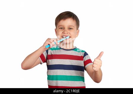 Smiling boy brushes his teeth and shows a thumbs up, isolated on a white background. Stock Photo