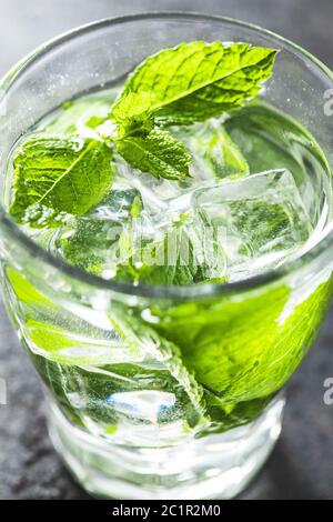 Cool drink with mint leaves and ice cubes on black table. Stock Photo