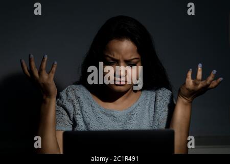 An Indian lady working late at night on her computer Stock Photo