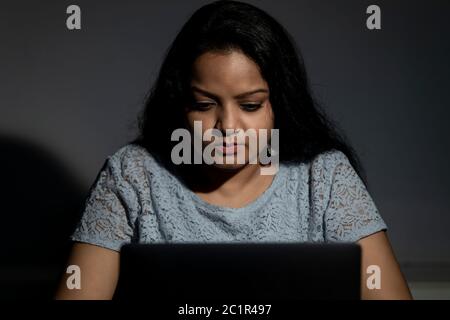 An Indian lady working late at night on her computer Stock Photo