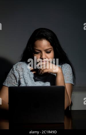 An Indian lady working late at night on her computer Stock Photo