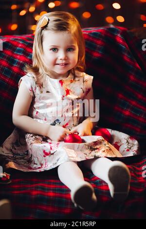 Smiling lovely baby girl in cute dress sitting on bench Stock Photo
