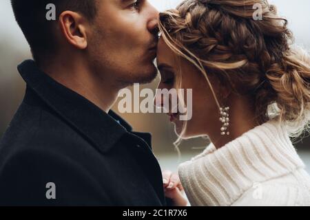 Groom kissing beautiful bride in forehead. Autumn wedding. Stock Photo