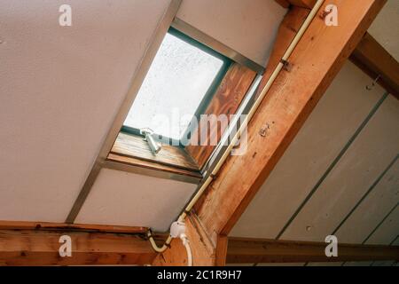 Attic, roof before construction with window and wooden beams Stock Photo