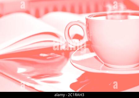 Living coral color of the Year 2019. Cup of coffee on the desk in the office. Retro toned. Stock Photo