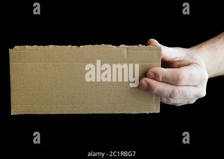 a hand holding a cardboard signboard with copy space and black background Stock Photo