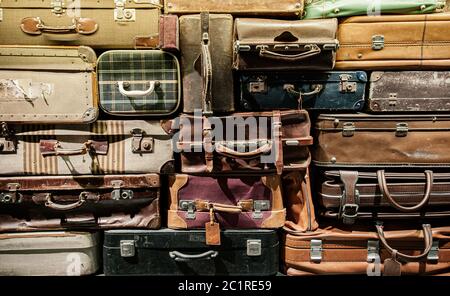 Stack of old assorted styles leather and fabric luggages. Vintage baggages background Stock Photo