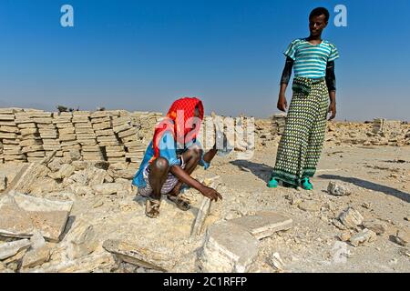 Workers cutting blocks of salt in a salt quarry at Assale Salt Lake, Hamedala, Danakil Depression, Afar Region, Ethiopia Stock Photo
