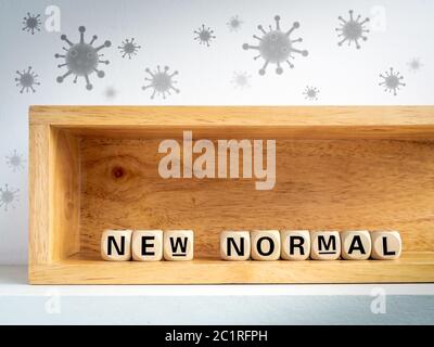 New Normal, words on wooden alphabet cube inside wooden box protecting virus floating in the air. New normal after covid-19 pandemic concept. Stock Photo