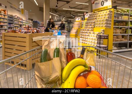 Grocery cart in supermarket filled with food products seen from the customers point of view Stock Photo