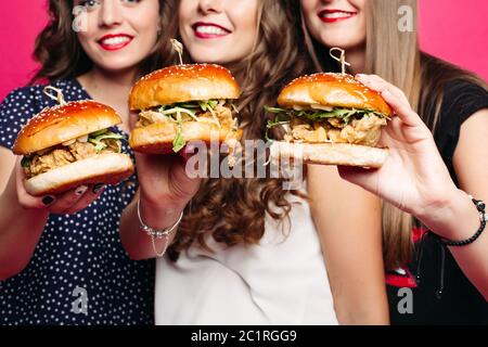 crop of friends holding yummy hamburgers with chicken and vegetables. Stock Photo