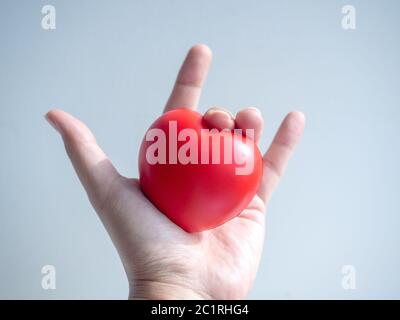 Red heart. big red heart ball in hand with i love you, hand sign on grey background. Stock Photo