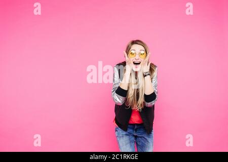 Emotion teen girl in yellow sunglaases against pink studio background. Stock Photo