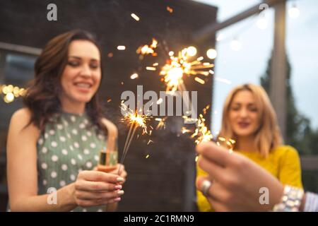 Group of partying girls with flutes with sparkling wine and bengal fire Stock Photo