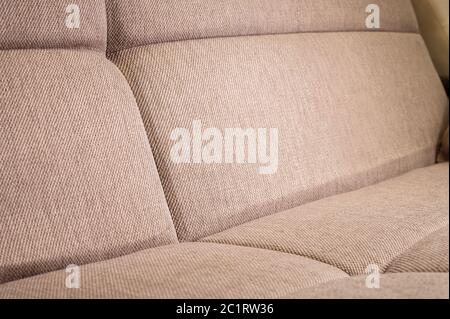 A close-up of a fragment of an expensive beige textile sofa in the room Stock Photo