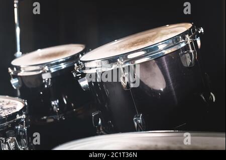 Closeup view of a drum set in a dark studio. Black drum barrels with chrome trim. The concept of live performances Stock Photo