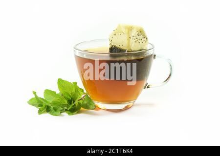 Healthy hot drink, herbal tea bag in a glass cup and a few fresh peppermint leaves isolated on a white background, copy space, selected focus Stock Photo
