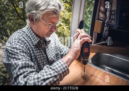 Senior man using a power drill Stock Photo