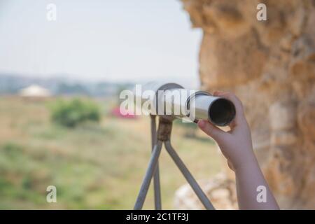 A child's hand holding a Telescopic monocular for landscape sightseeing Stock Photo