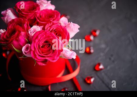 Pink roses bouquet packed in red box and placed on black stone background Stock Photo
