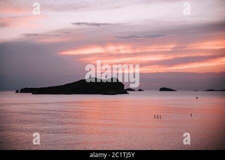 beautiful colors at sunset in ibiza on the sea. People doing paddle surf with a nice image Stock Photo