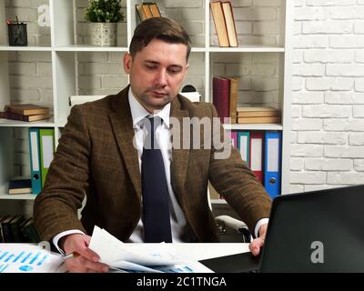 Businessman in a suit works with documents in the office. The workplace of the manager. Stock Photo