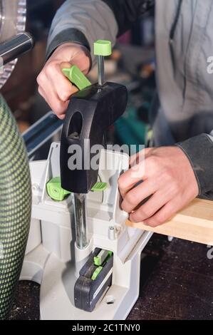 Close-up of the hands of a male carpenter set the workpiece in the clamps of a circular machine. Handwork. Starting a Business Stock Photo