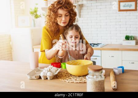 Mother and daughter prepare a cake together in the kitchen Stock Photo