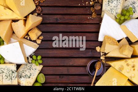 Various cheeses on wooden table with empty space. Stock Photo