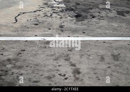 A white line painted horizontally on the gray dirty asphalt floor from use in an outdoor car park Stock Photo