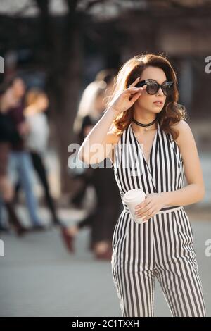 Woman in striped overalls posing with cup of coffee. Stock Photo