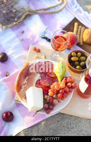 Picnic outdoor with rose wine fruits meat and cheese Stock Photo