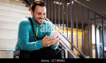 Portrait of young fit man athlete with mobile phone, bag after workout in gym