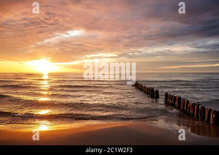 Beach with an old breakwater at beautiful sunset over sea. Stock Photo