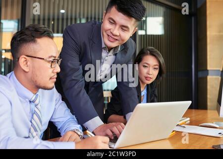Group of three modern office workers gathered together discussing issues of new business project Stock Photo
