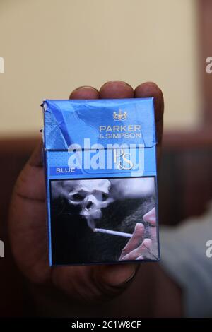 Hand holding Parker & Simpson cigarette packet with warning label picture,  Andoany/Hell-Ville City, Nosy Be, Madagascar Stock Photo