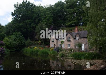 May 2020 (Lymm, Cheshire) A view of a village cottage row with tree's in the background and a village pond in the foreground Stock Photo