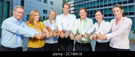 Successful group of business people in front of the office holds the thumbs up Stock Photo