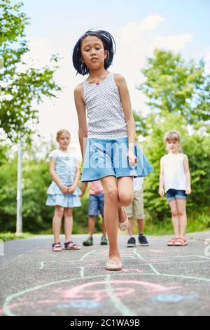 Children play a hopping game together in summer in kindergarten Stock Photo
