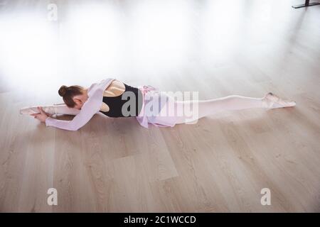 Caucasian female ballet dancer stretching out and focusing on her exercise Stock Photo