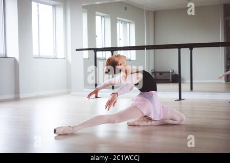 Caucasian female ballet dancer stretching out and focusing on her exercise Stock Photo