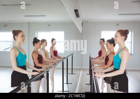 Caucasian female attractive ballet dancers doing exercises and holding a barre in a bright studio Stock Photo