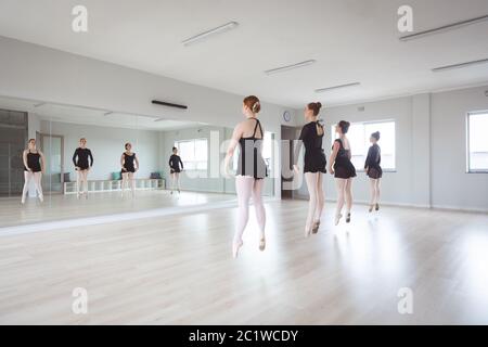 Caucasian female ballet dancers in black suits practicing during a class Stock Photo