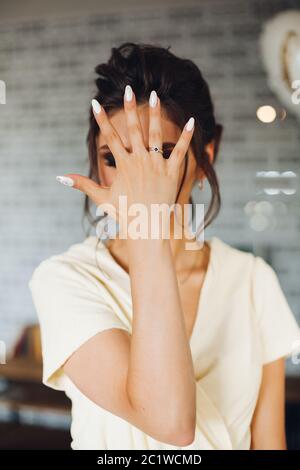 Brunette bride showing hand with wedding ring and hiding face. Stock Photo