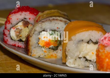 Sushi rolls with salmon, eel, cream cheese Philadelphia, caviar tobica and food sticks on the plate