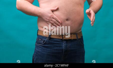 male with a big belly shows his fat on a green screen. The concept of healthy eating and losing weight, diet Stock Photo