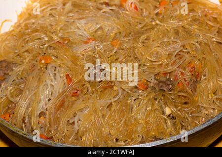 Fried funchoza with vegetables and chicken meat in a pan Stock Photo